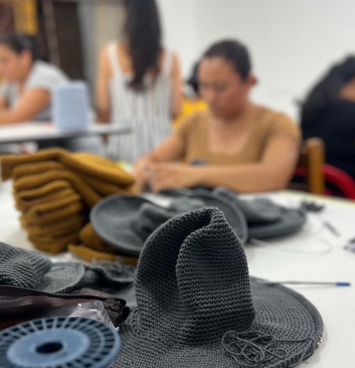 close up of almost finished crochet Sun hats in production workshop adding wire to brims of Sun hats