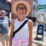 Woman wearing a crochet cottons floppy Sun hat straw hat and white tank top in the city street