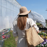 woman in garden hat buying starter plants at greenhouse