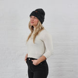 Woman styled charcoal winter beanie that is chunky knit, folded up with a thick cuff.