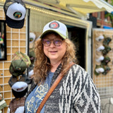 A Woman wearing the North Ferry "Library Guardian" Mincing Mockingbird Trucker Caps at our mobile hat trailer. A gift for this Librarian Mom of Corning NY