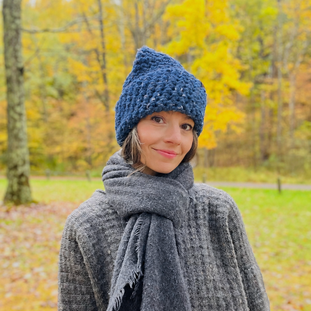 North Ferry Chunky Knit Beanie in Bright Bomber Blue being worn on a woman hiking a trail, layered in knits. 