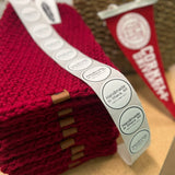 Stack of red fabric items with 'handmade in America' labels on a wooden surface.