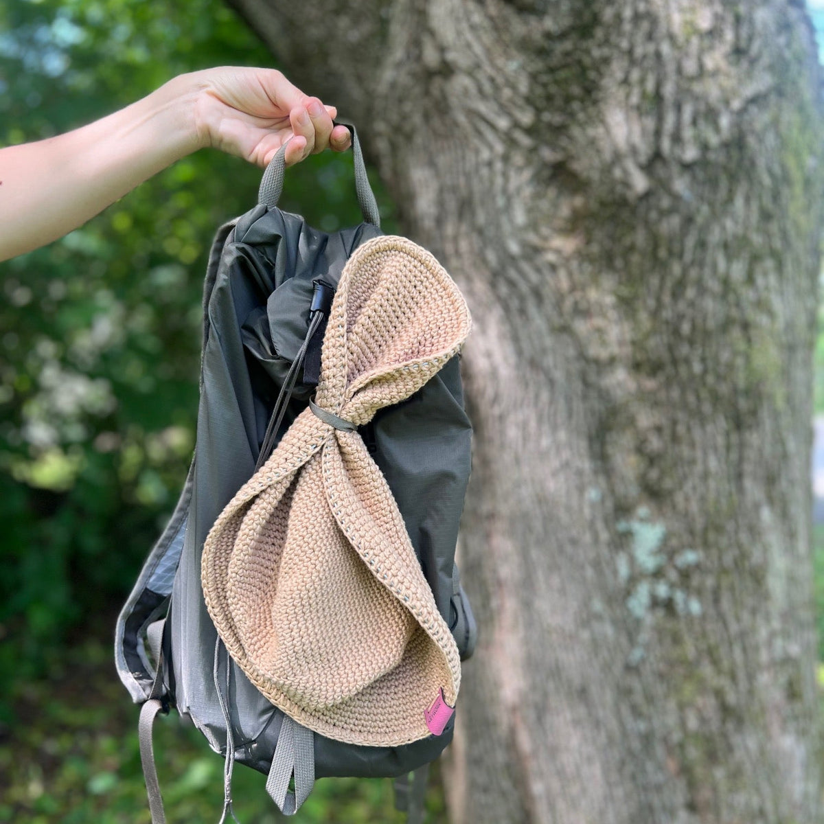 A Packable Sun Hat in a strap on a small hiking back pack that shows packability and soft fabric