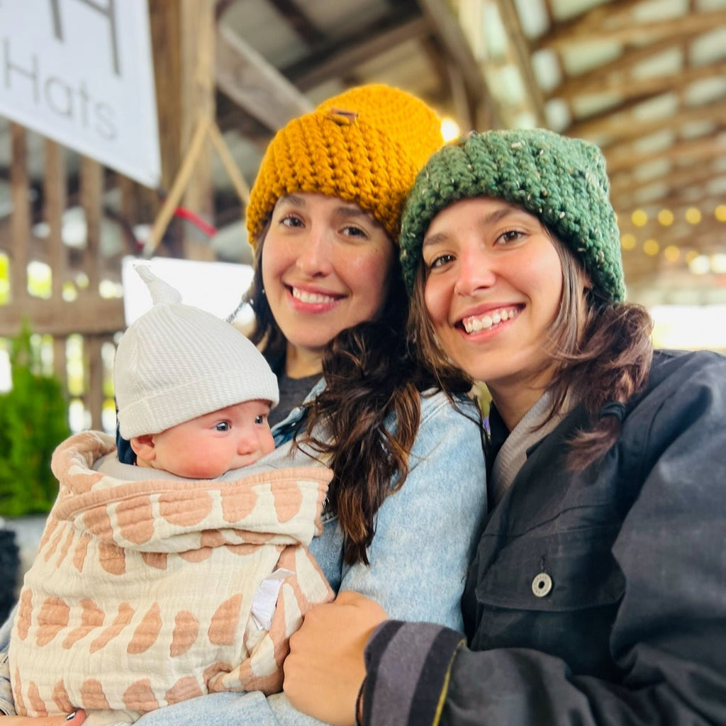 Two young women (one is a mom) wearing matching beanies in gold and green. Thick Knit and Folded up Cuff 