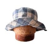 Plaid bucket hat on a wooden block against a white background Reversible Waterproof Bucket Hats and Sun Hats made from Upcycled fabrics