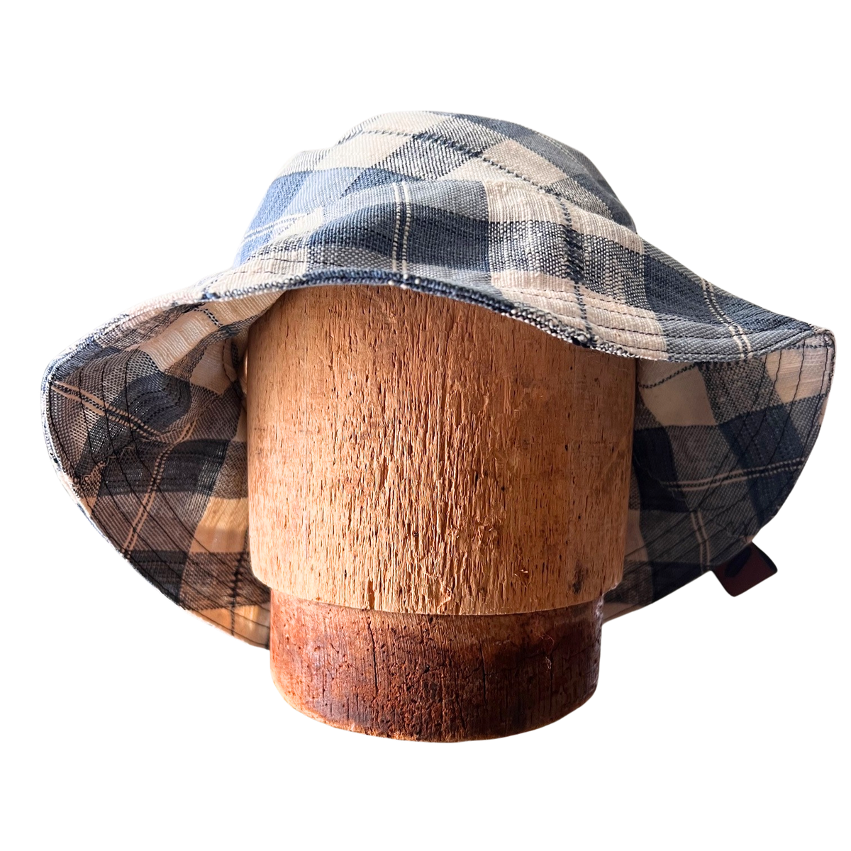 Plaid bucket hat on a wooden mannequin head against a white background