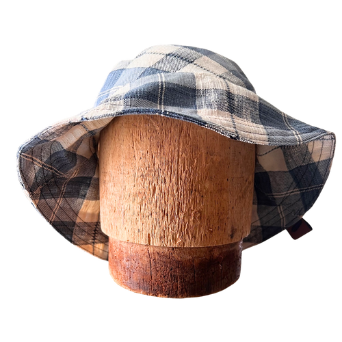 Plaid bucket hat on a wooden mannequin head against a white background