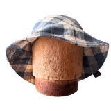 Plaid bucket hat on a wooden mannequin head against a white background