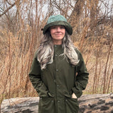 The owner of North Ferry Hats in Patagonia rain jacket and North Ferry Reversible Bucket Hat that has a puffy quilted teal floral fabric on one side, and a satin mix green floral fabric on the other side. 