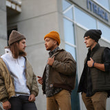 3 men wearing North Ferry Chunky Knit Beanies in brown, gold, and charcoal and styled in a variety of ways. North Ferry Beanies can be worn big and baggy or rolled up with a cuff. 