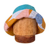 Colorful patchwork sun hat on a wooden block against a white background Kid Bright Geometric Prints and Vintage Cotton lining