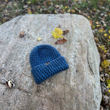 Blue knitted beanie on a rock by a body of water
