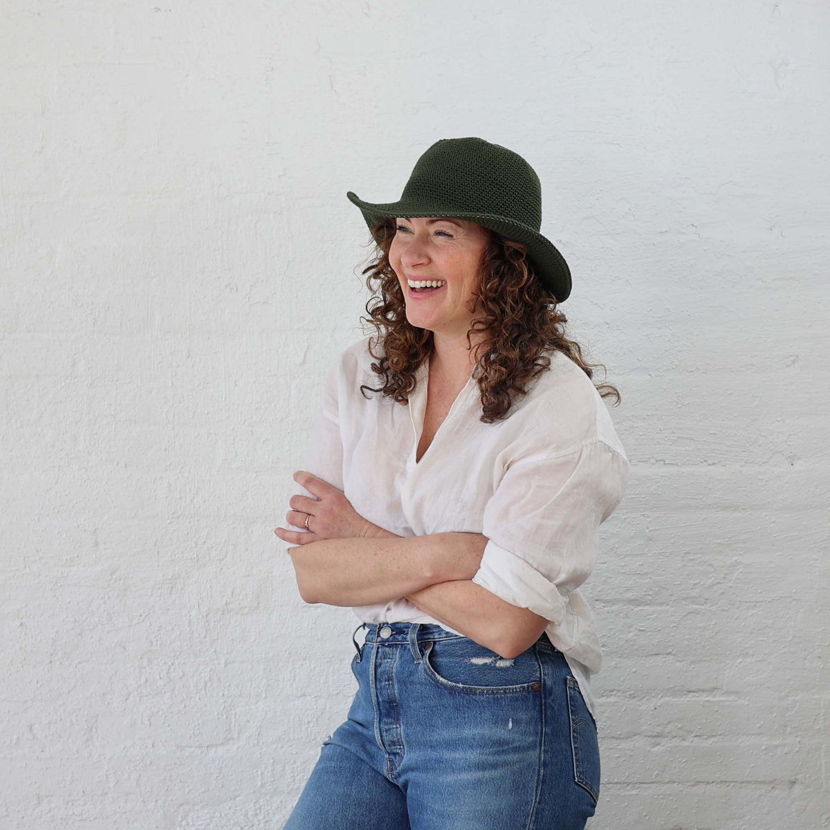 Leaf Green Crochet Cotton Packable Sun Hat modeled on a female with curly hair to show how stretchy and versatile the sizing is