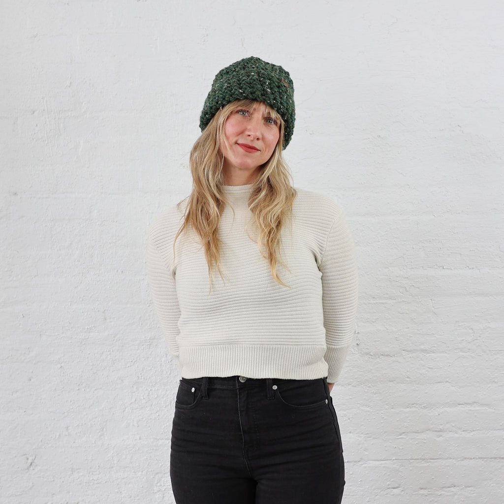 Thick Green Winter Hat styled on woman, folded up with a thick wide cuff. Green Tweed speckled yarn 