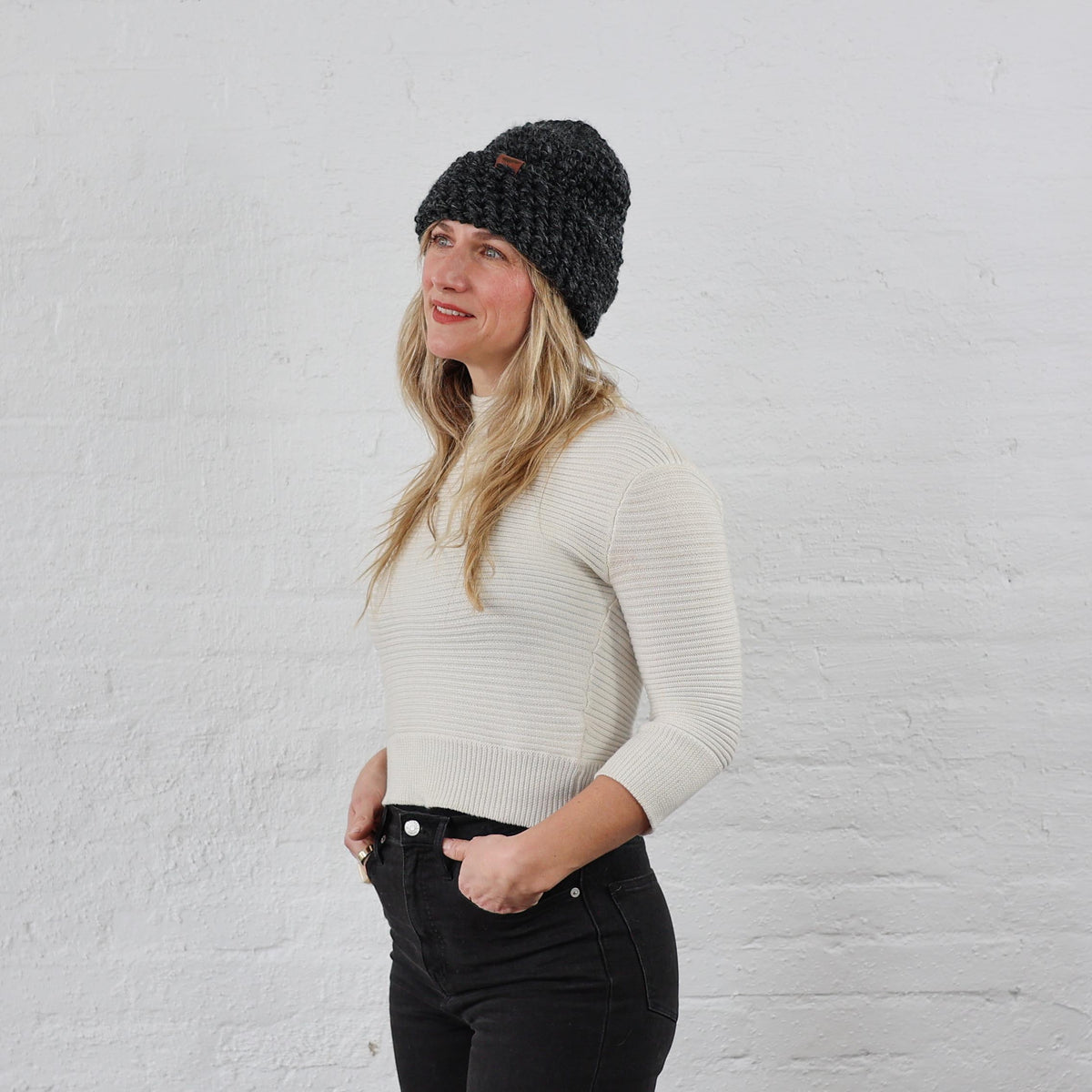 Woman styled charcoal winter beanie that is chunky knit, folded up with a thick cuff. 